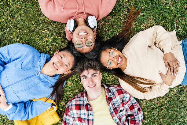 istock Young student friends having fun on the grass together looking to the camera 1558208627