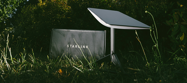 Germany - Jun 16, 2023: Cardboard parcel in backyard at night. Flash photography, no people. Is it a SpaceX Starlink delivery, setting up communication anywhere, even in wilderness spots