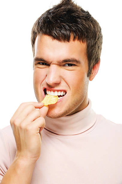 portrait of young man eating chips stock photo