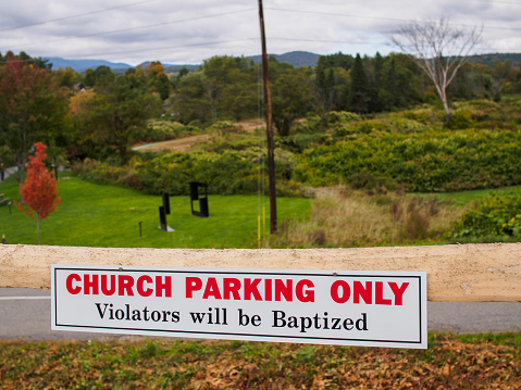 Funny sign outside a church in Stowe, Vermont, USA, with mountains in the background \