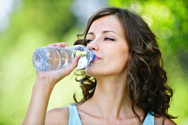 young dark-haired woman drinking water stock photo