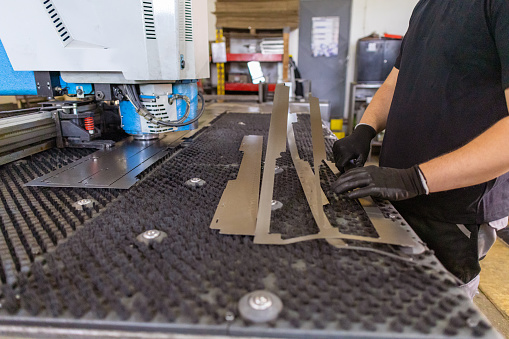Stock photo of an employee using a laser cutting machine for precise cutting in the factory.