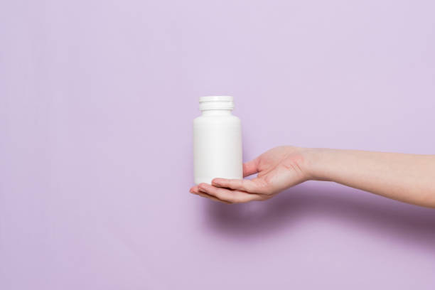 istock White plastic bottle in female hand. Packaging for pills, capsules or supplements. 1558259450