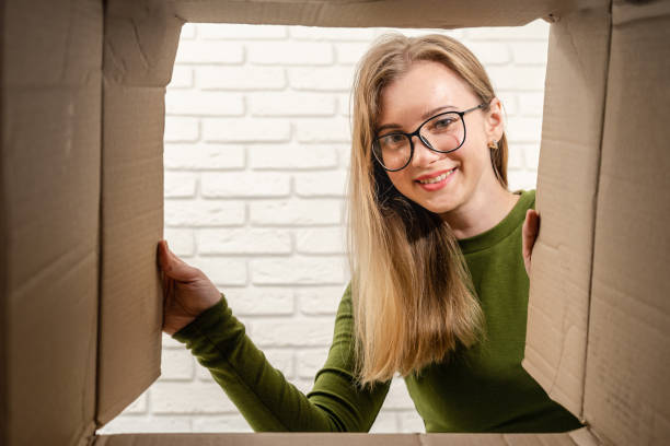 istock Happy female client opening a carton box and looking inside. Delivering parcel, unpacking. 1558260017