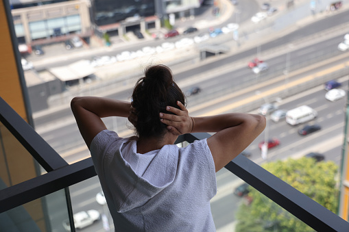 Woman is overwhelmed by city noise and covers her ears with her hands