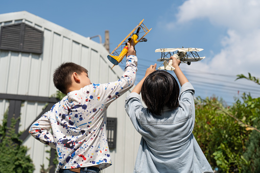 Two Asian boy playing toy airplane model at home. Kids dream to pilot and fly to sky