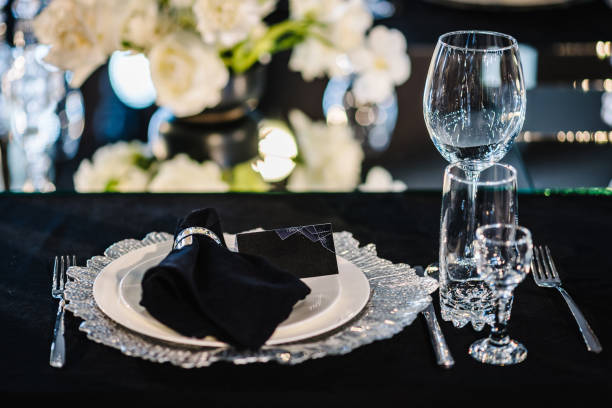 istock Serving, setting table. Plate and glass, stack, wineglass, luxury black rich decor. Side view. Closeup. Wedding set up, dinner table reception. Birthday, baptism, event. Closeup details interior. 1558296642