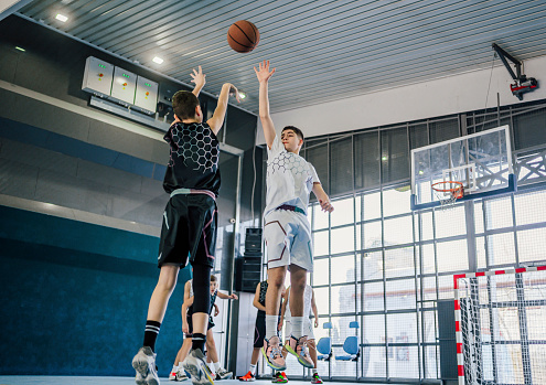 Male teen basketball team on an indoor court, playing basketball