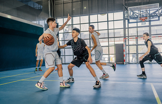 Young male teens playing basketball on an indoor court