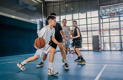 Young man picking up his friend off the ground. Group of friends playing a basketball game outdoors.