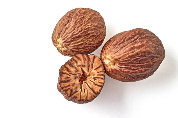 trois noix de muscade, entières et moitié, isolées sur fond blanc - nutmeg photos et images de collection