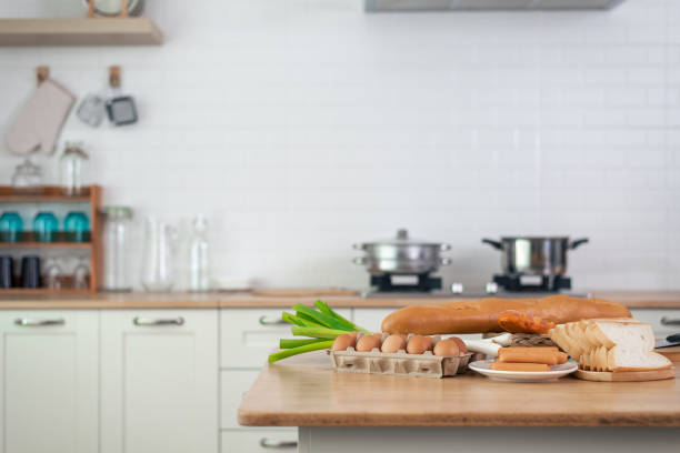 Baking materials are set out on a wooden table, ready for cooking. To copyspace text. Concept of cooking with a kitchen in the background.