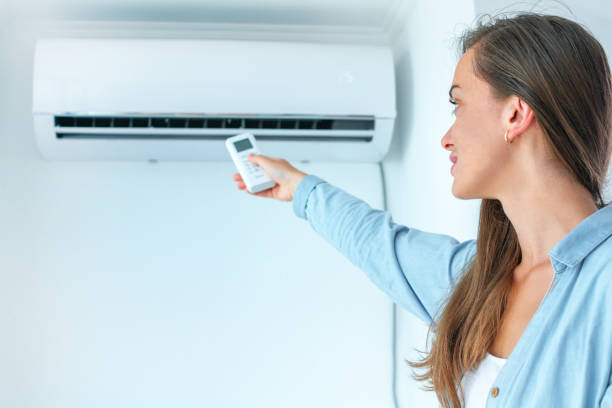 istock Young attractive woman using remote controller for adjustment air conditioner temperature in room at home 1558367647