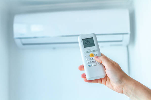 istock Air conditioner temperature adjustment with remote controller in room at home 1558368172