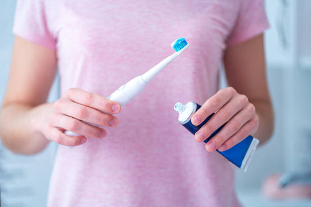 istock Brushing teeth using ultrasonic electric toothbrush and toothpaste in bathroom at home. Oral hygiene, dental and gum health 1558371971