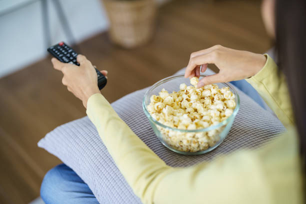 istock Asian woman Watching smart TV and using remote controller Hand holding television audio remote control at home with the remote control television 1558375824