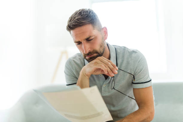 istock Worried middle-aged man reading unexpected paper document. 1558389868