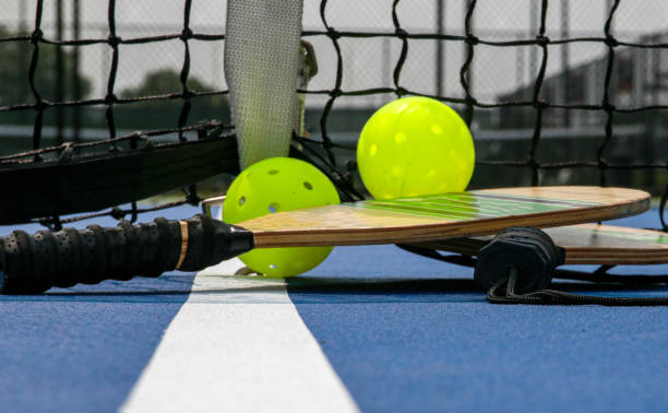 istock Two pickleball paddles and two yellow whiffle balls 1558409140