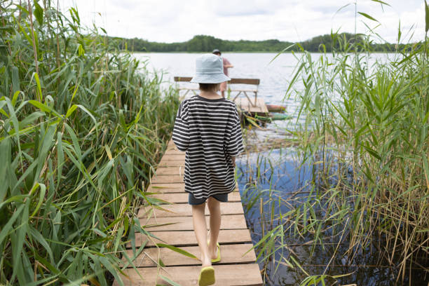 Only Young boy on a pier near lake.