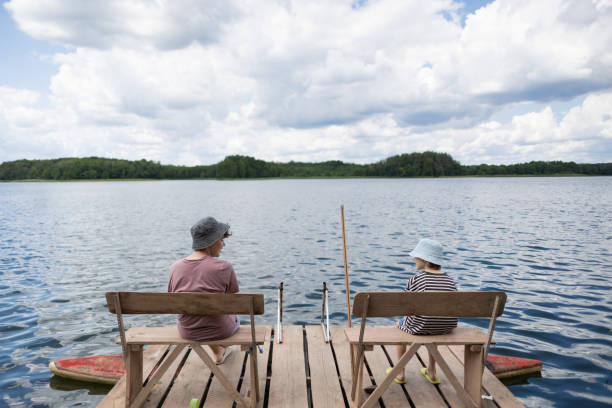 istock Two boys sitting on a pier near lake 1558427680
