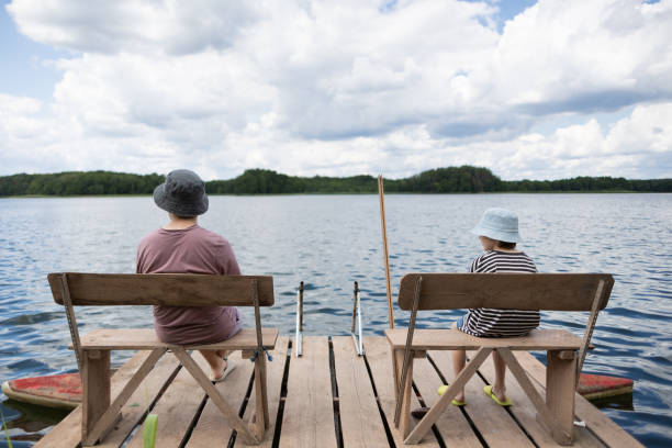istock Two boys sitting on a pier near lake 1558427940