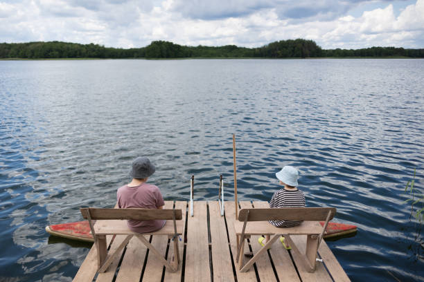 istock Two boys sitting on a pier near lake 1558427942