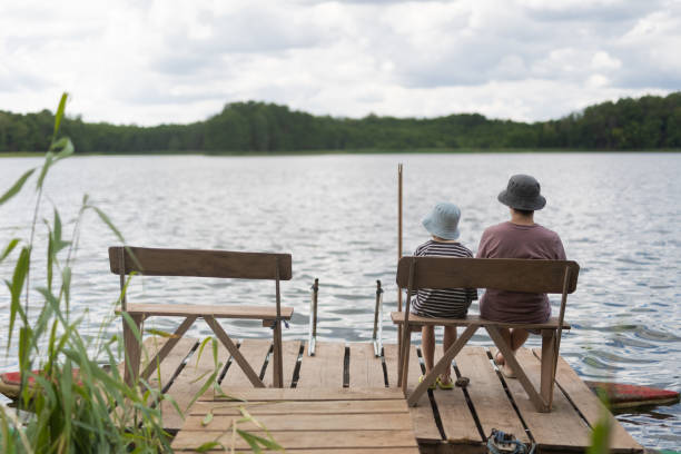 istock Two boys sitting on a pier near lake 1558431923