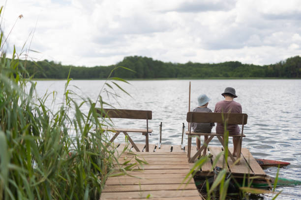 istock Two boys sitting on a pier near lake 1558432435