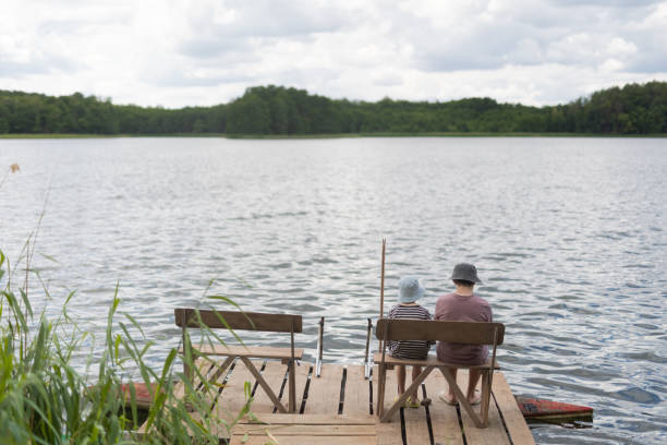 istock Two boys sitting on a pier near lake 1558432446