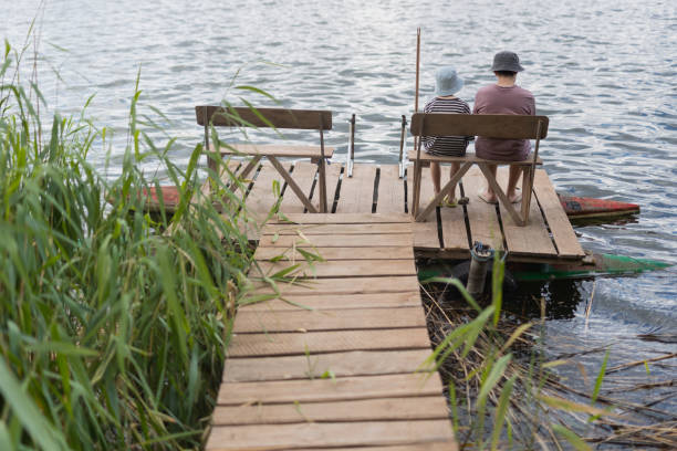 istock Two boys sitting on a pier near lake 1558432455