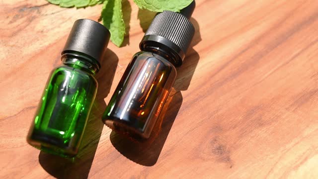 Brown and green bottles of essential oils. natural cosmetics for skin care. A bottle and fresh mint on a wooden table. Taking care of health and beauty.