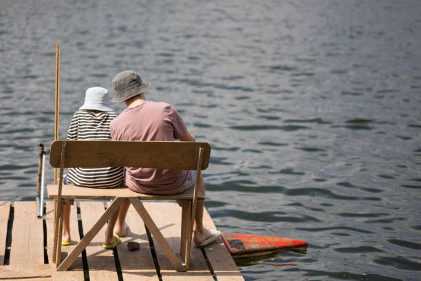 istock Two boys sitting on a pier near lake 1558433008