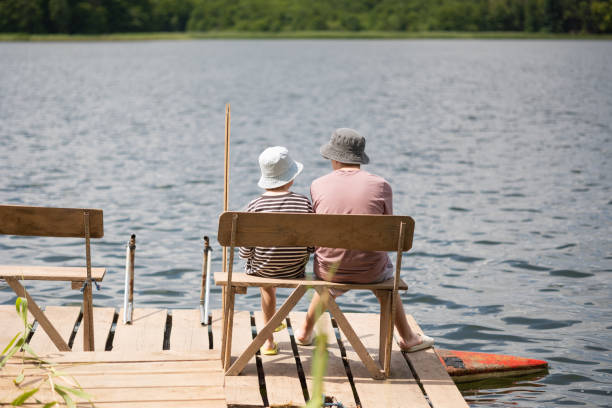 istock Two boys sitting on a pier near lake 1558433076