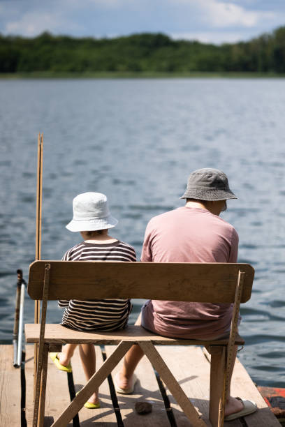 istock Two boys sitting on a pier near lake 1558433539