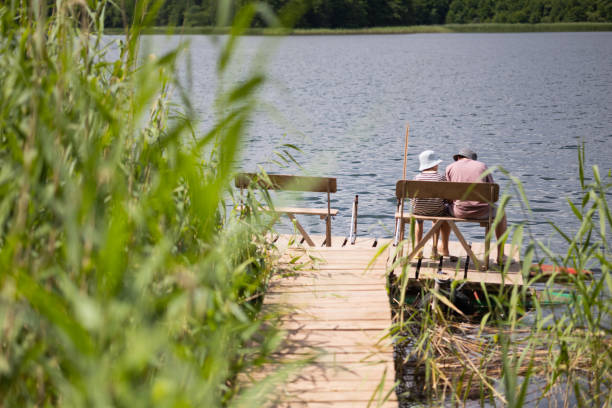 istock Two boys sitting on a pier near lake 1558434072