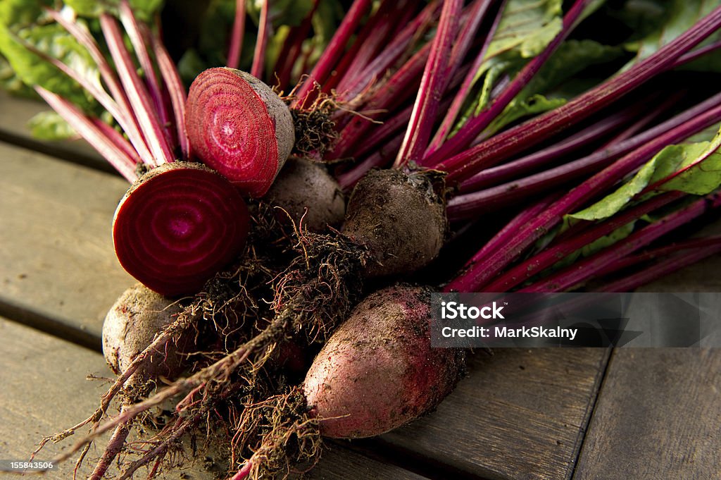 Raw organic beet roots both whole and halved Fresh organic beets just picked from the garden shot on a wood table. Backgrounds Stock Photo