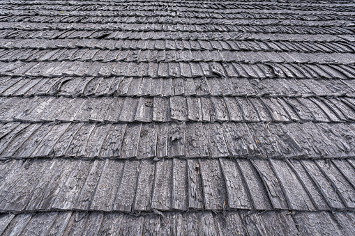 Fragment of an old traditional wood chip roof. The material of the roof is very aged with time and weather