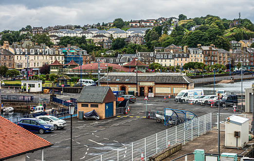 Rothesay, Scotland - 18th July 2023: Part of the seaside town of Rothesay on the Isle of Bute, showing the pier at the Ferry Terminal,, part of the harbour and esplanade, the Victorian Toilets and the Winter Gardens
