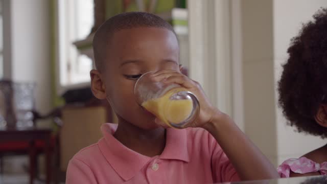 Boy drinking orange juice during breakfast at home