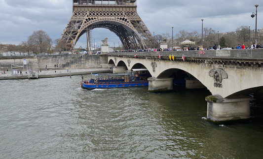 Paris, France - March 19, 2023: Crowd of people over the Jena Bridge next to the Eiffel Tower in Paris, France.