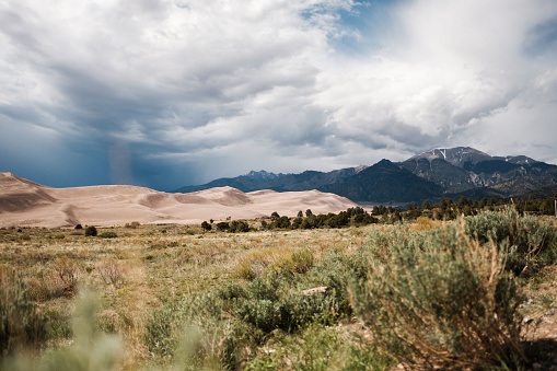 Sandy dunes and a dry grassland with a mountain in the backdrop, Great Sand Dunes National Park