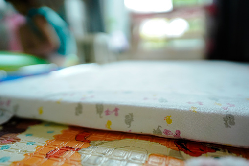 Close up latex mattress in chiildren play room at home.Little girl on soft blur background.