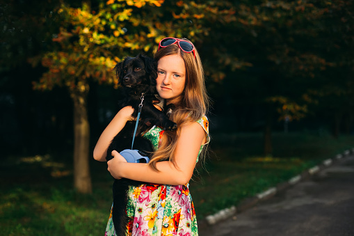 Young girl in a summer dress holding her pet with love and looking at camera