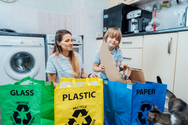 istock Mother is teaching kid how to recycle help the boy aware environmental importance - mom educates son sort garbage into different bins on kitchen. Family sorting garbage at home. Concept of recycling 1558511208