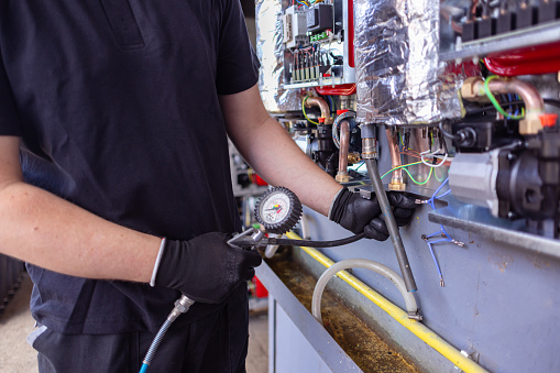 Close-up shot of an employee using a pressure gauge on the machine.