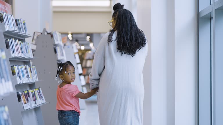 Mixed race girl with mother in library, looks over shoulder