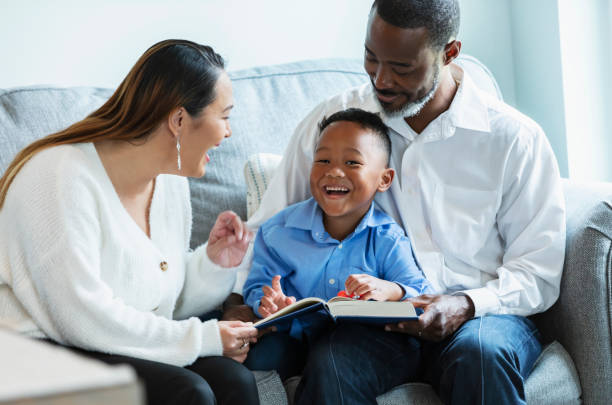 istock Multiracial young boy with parents, reading book on sofa 1558586242