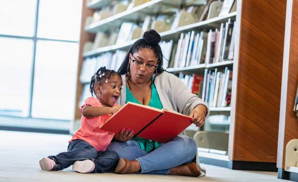 도서관에서 어머니와 함께 책을 읽고 있는 흥분된 어린 소녀 - picture book library preschool bookshelf 뉴스 사진 이미지