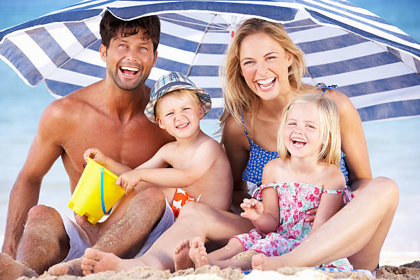 istock Family Sheltering From Sun Under Beach Umbrella 155862975