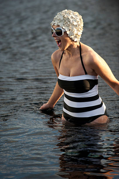 Woman in floral swim cap and sunglasses getting into pool Woman in floral swim cap and sunglasses.getting into a cold pool, early evening. Funchal, Madeira flower swim hat stock pictures, royalty-free photos & images